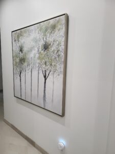 portfolio image of white and green painting of trees hanging in hallway