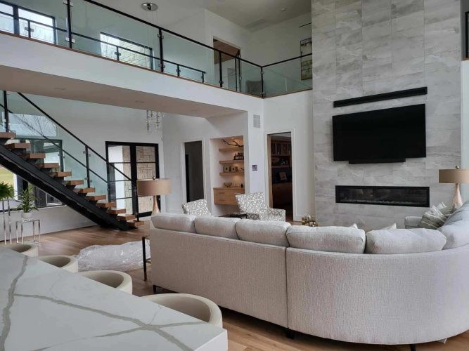 portfolio image of large living room with couch, tv, and marble fireplace