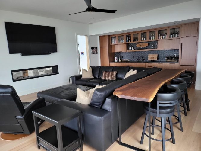 portfolio image of living room with large black couch, bar, and tv