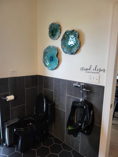 portfolio image of bathroom with black toilet and urinal and blue wall art